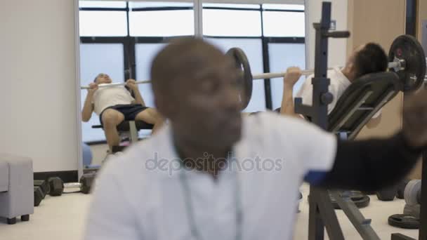 微笑的私人教练监督客户在现代健身房的肖像 — 图库视频影像