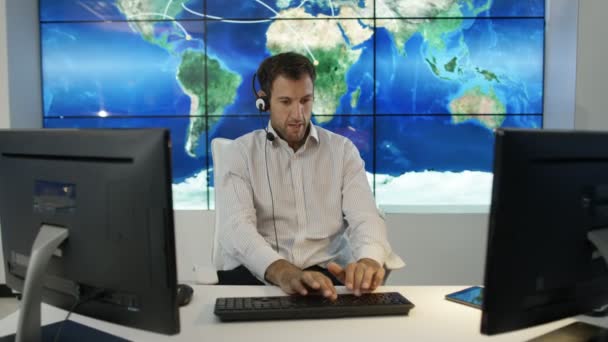 通过耳机与大世界地图图形在视频墙上交谈的商人 — 图库视频影像