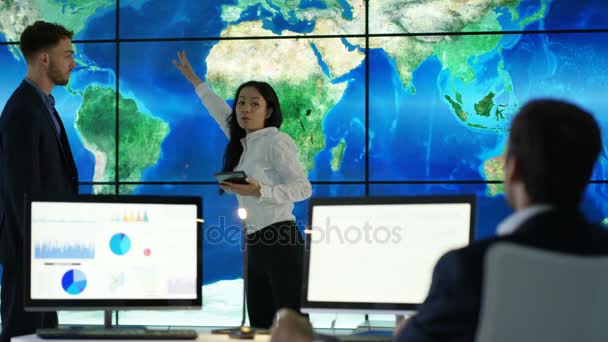 商务团队讨论视频墙上的大型世界地图图形 并在计算机屏幕上显示饼图和图形 — 图库视频影像