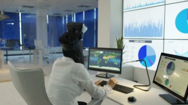 4k işkadını, fütüristik office sanal gerçeklik kulaklık ile etkileşim gösteren finansal bilgi ve Dünya Haritası bilgisayar ekranları