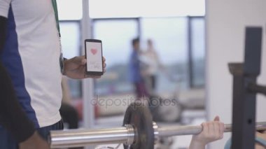 Spor salonunda bir müşteri ile akıllı telefon App-e doğru tren kullanarak fitness eğitmeni