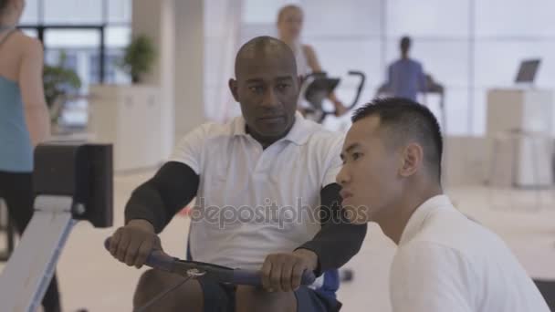 Hombre Haciendo Ejercicio Gimnasio Siendo Supervisado Por Instructor Fitness — Vídeos de Stock