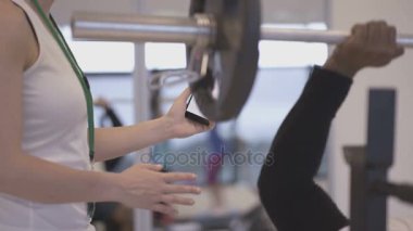 Spor salonunda bir müşteri ile akıllı telefon App-e doğru tren kullanarak fitness eğitmeni