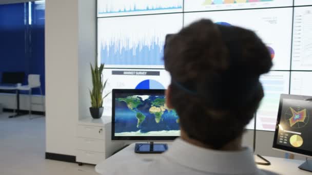 未来オフィスに仮想現実のヘッドセットとの相互作用の実業家 コンピューターの画面表示の金融情報や世界地図 — ストック動画