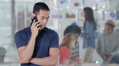 4k başlangıç şirket işadamı arka planda çalışan personel ile telefonda konuşurken gülümseyen portresi