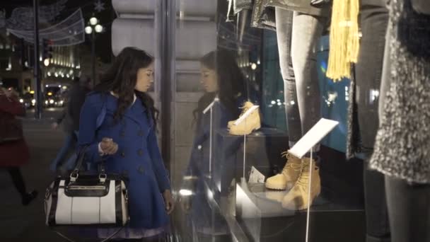 有魅力的年轻妇女在商店窗口看在城市在晚上 — 图库视频影像