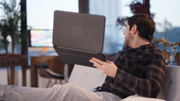 のカジュアルな人のホーム ビデオ チャットを持つラップトップ コンピューターで彼のアパートを示すでリラックス — ストック動画