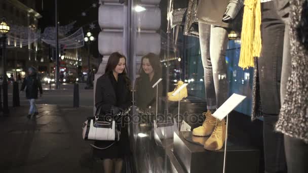 有魅力的年轻妇女在商店窗口看在城市在晚上 — 图库视频影像