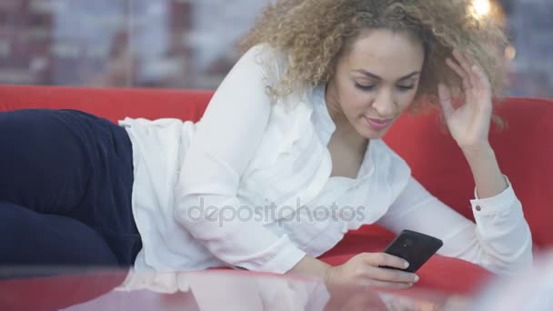 魅力的な女性は家でのんびりとスマート フォン上にテキスト メッセージ — ストック動画