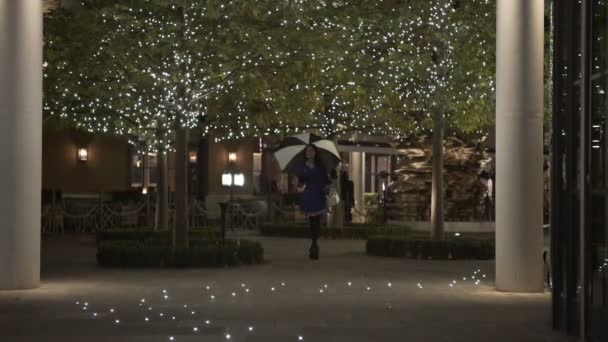 美丽的妇女用雨伞穿过城市在晚上 — 图库视频影像