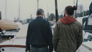 4k görüntülemek arkadan baba ve oğlu bir Marina iskele boyunca yürüyüş