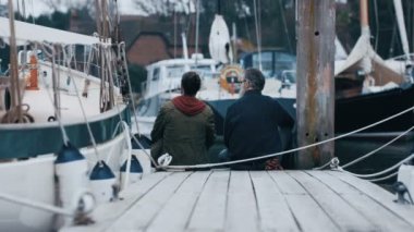 4 k baba ve oğlu huzurlu zevk iskelede oturup ve sohbet zaman