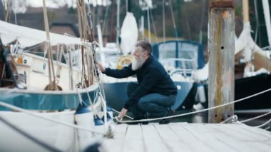 4k olgun sakallı adam onun tekne yat limanı iskele için bir yelken gezisi sonra demirleme.