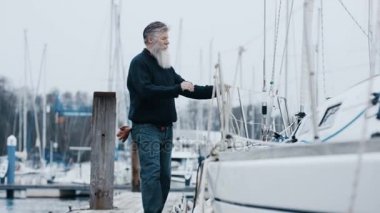 4k olgun sakallı adam Marinada, demirledi tekne ile bir yelken gezisi için hazırlanıyor.