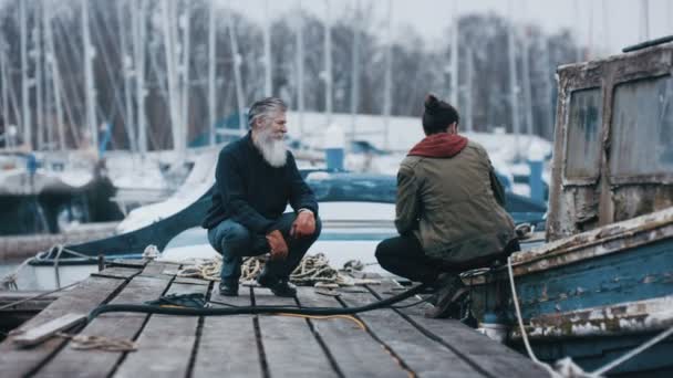 与被殴打的老船的父亲和儿子的渔民系泊它跳船和聊天 — 图库视频影像