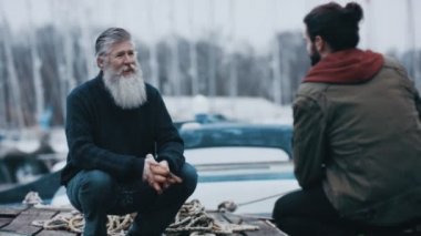 4 k baba ve oğul iskelede oturup ve sohbet bir yelken gezisi
