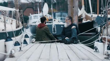 4 k baba ve oğlu huzurlu zevk iskelede oturup ve sohbet zaman