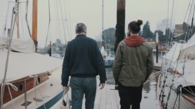 4k görüntülemek arkadan baba ve oğlu bir Marina iskele boyunca yürüyüş