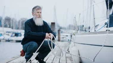 4k olgun sakallı adam Marinada, demirledi tekne ile bir yelken gezisi için hazırlanıyor.