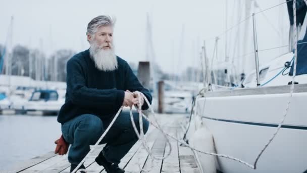 Зрілий Бородатий Чоловік Човном Прикріпленим Яхти Готується Вітрильної Подорожі — стокове відео