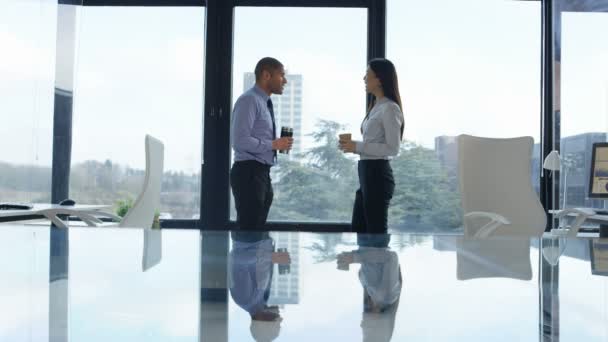 ビジネスの男性と女性のコーヒーは 大規模なオフィスの窓の前でチャット — ストック動画
