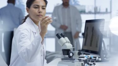 mikroskop altında bir slayt bakarak ve bilgisayarda çalışan 4 k tıp araştırmacısı