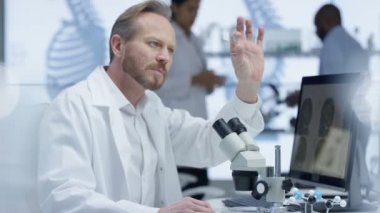 mikroskop altında bir slayt bakarak ve bilgisayarda çalışan 4 k tıp araştırmacısı