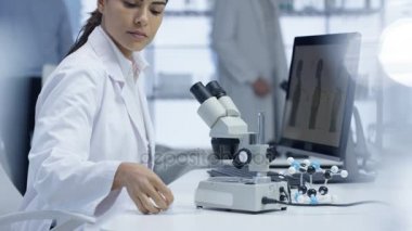 mikroskop altında bir slayt bakarak ve bilgisayarda çalışan 4 k tıp araştırmacısı