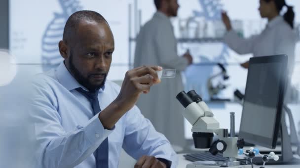 Investigador Médico Mirando Una Diapositiva Bajo Microscopio Trabajando Computadora — Vídeo de stock