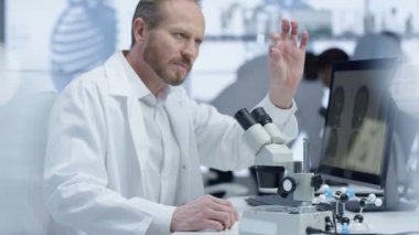 mikroskop altında bir slayt bakarak ve bilgisayarda çalışan 4 k tıp araştırmacısı