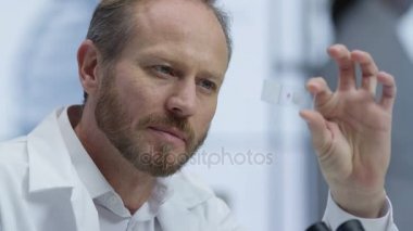 tıbbi araştırmacı laboratuarda mikroskop altında bir slayt bakarak 4k yakın çekim