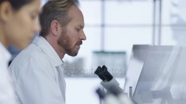 4 k tıp araştırmacısı laboratuvardaki bilgisayarda çalışarak ve mikroskop arıyorum