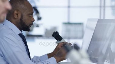 4 k tıp araştırmacısı laboratuvardaki bilgisayarda çalışarak ve mikroskop arıyorum