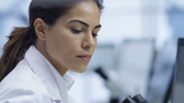 4K Chercheur médical regardant une diapositive au microscope et travaillant sur ordinateur 