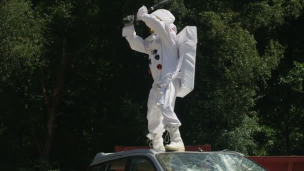 积极的宇航员站在车上 用棒球棍砸车 — 图库视频影像