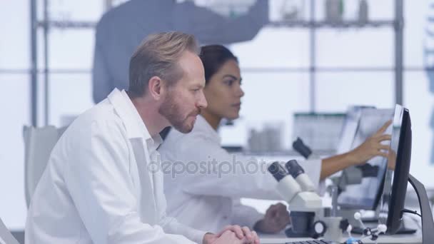 4K Chercheurs médicaux dans le laboratoire, travaillant sur des ordinateurs et discutant de leur travail .