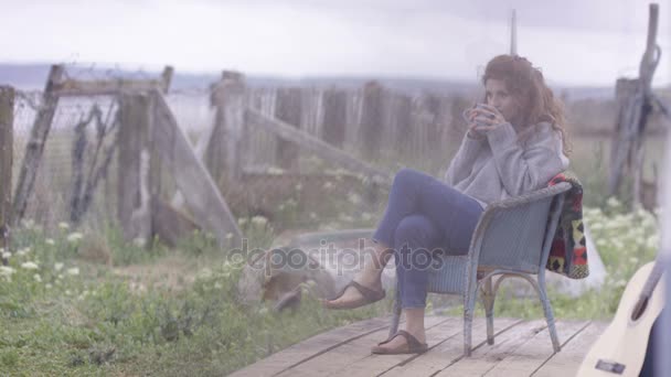 若い女海の家でのリラックス ポーチに座って 景色を眺めて — ストック動画