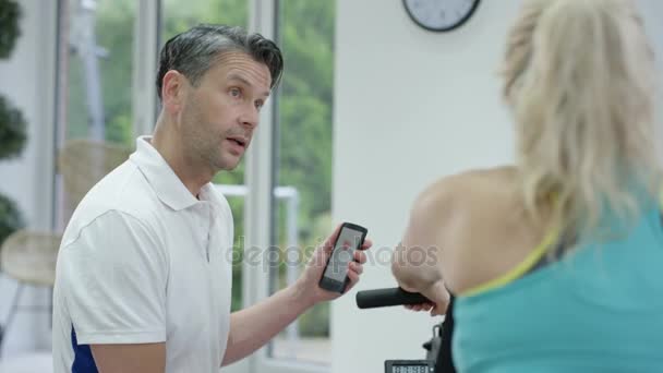 Entrenador Fitness Usando Aplicación Para Teléfonos Inteligentes Para Entrenar Clientes — Vídeos de Stock