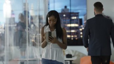 Arka planda tablet bilgisayar, iş arkadaşları ve şehir manzaralı neşeli işkadını portresi.