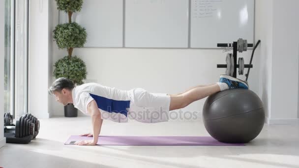 健康的成熟的男人锻炼与健身球在健身房 — 图库视频影像