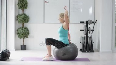 4 k sağlıklı Olgun kadın fitness topu ve direniş grubu içinde jimnastik salonu ile çalışma dışarı