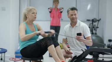 4k Olgun kadın müşteri eğitmek için smartphone app kullanarak Fitness eğitmeni