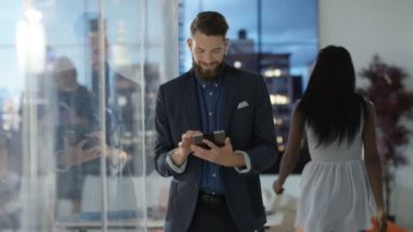 Arka planda tablet bilgisayar, iş arkadaşları ve şehir manzaralı neşeli işadamı portresi.