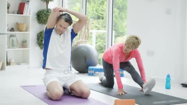 4 k sağlıklı Olgun çift katta tablet ile birlikte Yoga egzersiz yapıyor