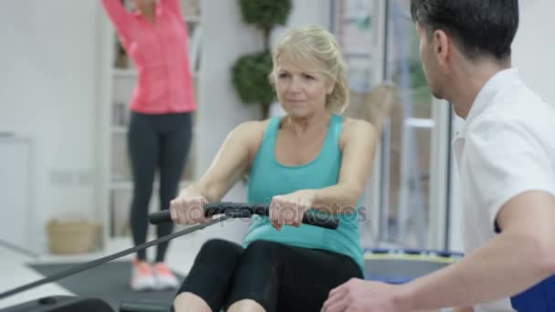 Mujer Madura Haciendo Ejercicio Remo Con Entrenador Personal — Vídeos de Stock