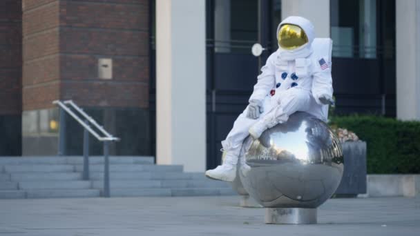 Смішний Астронавт Розслабляється Сидить Металевій Сфери Скульптури Міській Вулиці — стокове відео