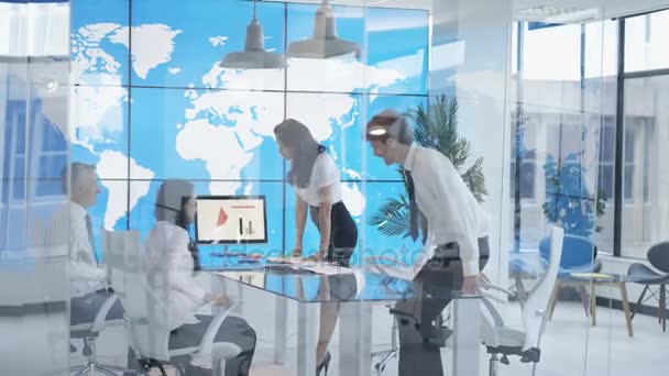4 k mezinárodní obchodní tým mají schůzku v kanceláři s mapou světa na video zeď