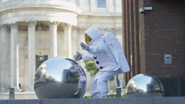 有趣的宇航员返回地球 试图拿起一个金属球体雕塑 — 图库视频影像