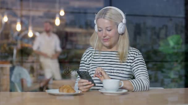 Wanita Muda Minum Kopi Dan Mendengarkan Musik Dengan Smartphone Kafe — Stok Video