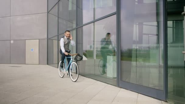 在进入办公大楼前 骑自行车的商人用手机交谈 — 图库视频影像